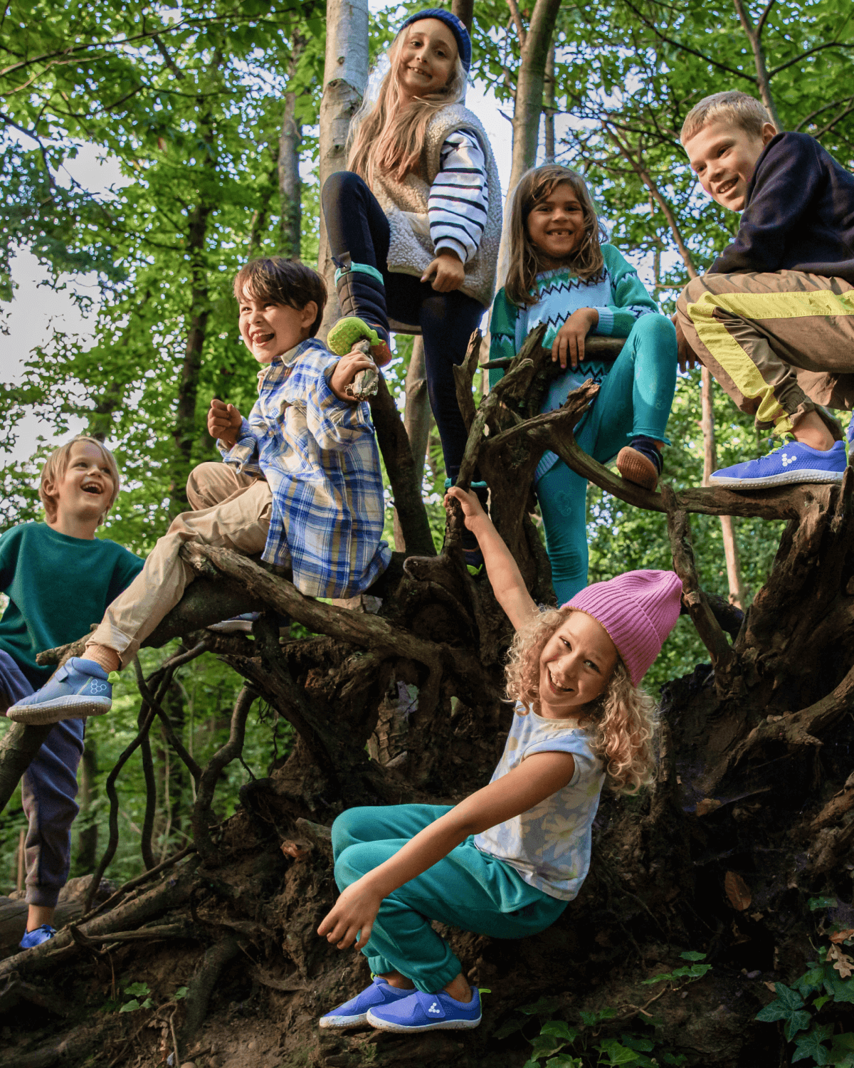 Six kids playing around a tree stump outside wearing flexible lightweight barefoot kids shoes.