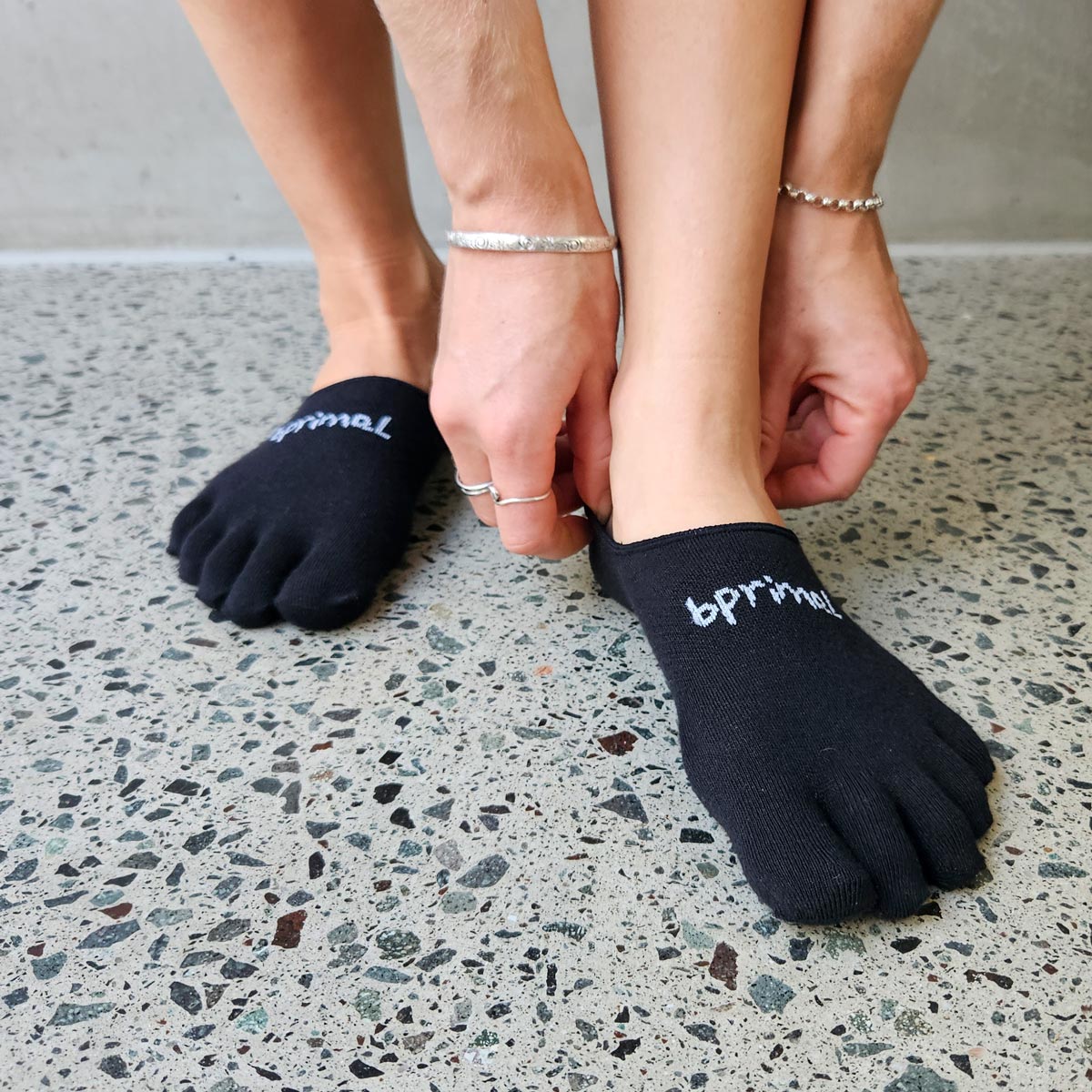 Close up of a person pulling on a pair Black Bprimal Everyday Five-Toe Socks - Hidden