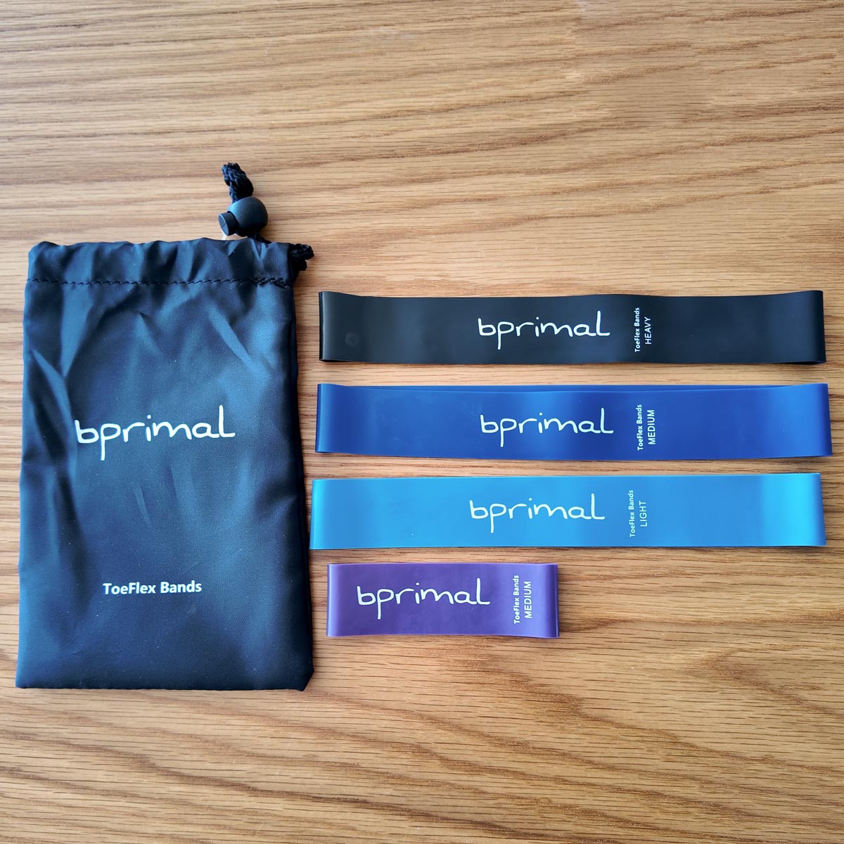 bprimal ToeFlex Bands with a drawstring bag on a wooden background