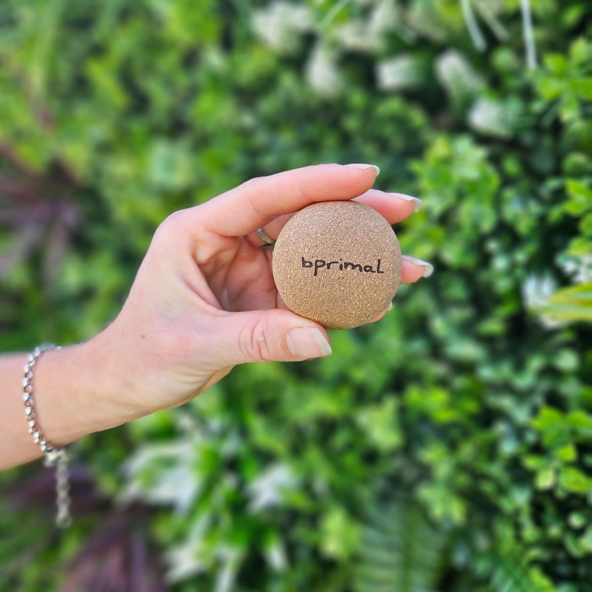 Hand holding a Bprimal Cork Massage Ball with &
