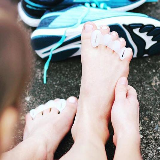 Person sitting on pavement wearing bprimal Correct Toes® - Toe Spacers