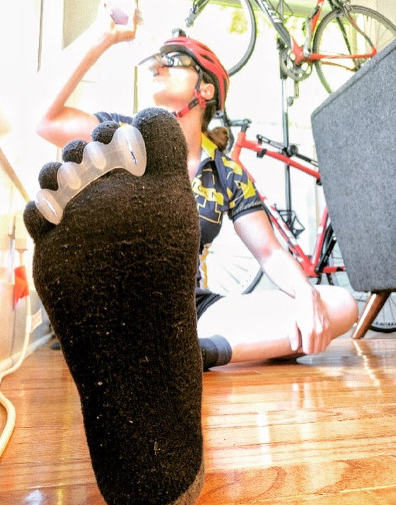 Cyclist wearing bprimal Correct Toes® - Toe Spacers over socks