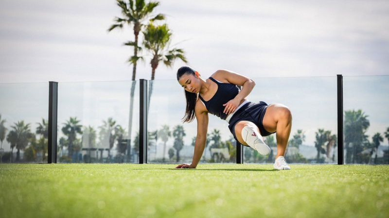 A woman exercising outdoors on grass wearing wearing Vivobarefoot Motus womens barefoot sneakers for performance training