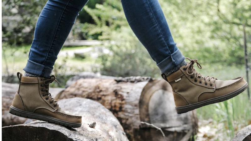 Person walking on logs outdoors wearing Lems barefoot boots designed for comfort, flexibility, and natural foot movement.