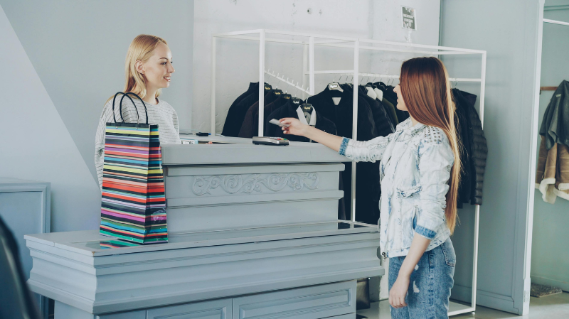 Customer paying at retail counter in clothing store, suitable for barefoot work shoes in hospitality and retail environments