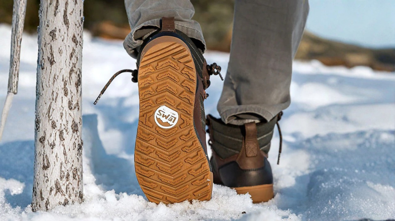 Person wearing Lems barefoot boots in snow, highlighting waterproof protection, rugged tread pattern, and natural movement for winter hiking.