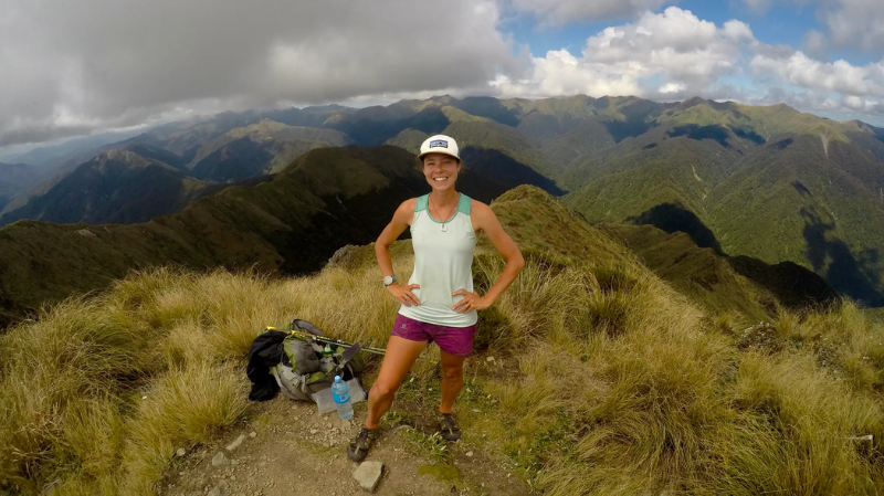 Nat Gallant – Physiotherapist & Running Technique Coach standing on a mountain trail with scenic peaks and valleys in the background during an outdoor run