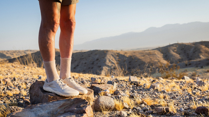 Person standing on rocky terrain wearing Vivobarefoot shoes, showcasing zero drop footwear designed for natural movement and outdoor exploration.