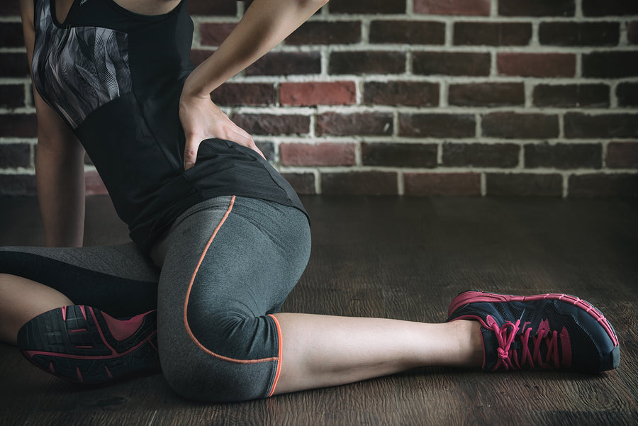 Person stretching indoors while wearing barefoot training shoes designed to support natural movement and flexibility.