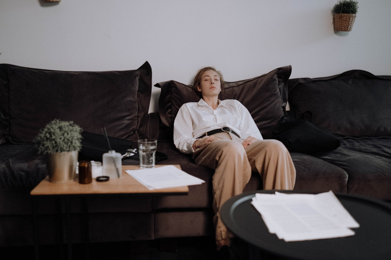 Person lying on a couch appearing fatigued and exhausted, representing low energy or burnout.