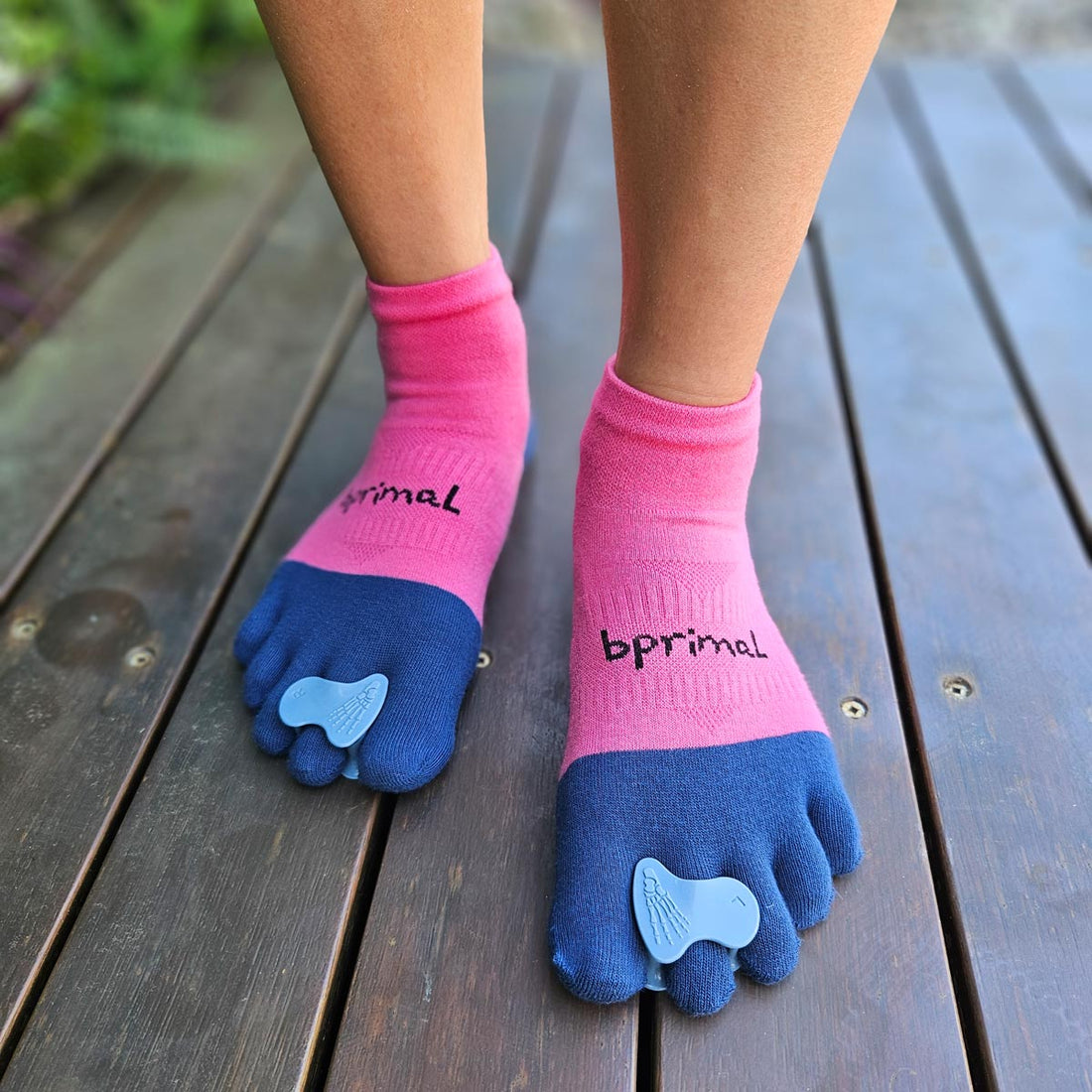 Person wearing Correct Toes - Stable Toe over pink and blue bprimal toe socks standing on timber deck