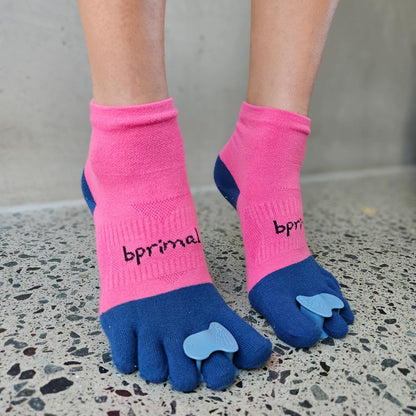 Person wearing Correct Toes - Stable Toe over pink and blue bprimal toe socks indoors