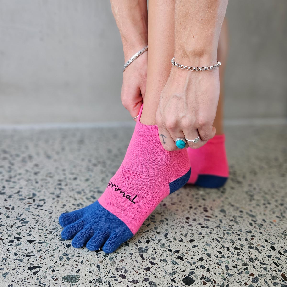 Person pulling on pink and navy Bprimal Womens Performance Five-Toe Socks