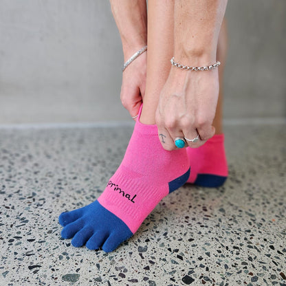 Person pulling on pink and navy Bprimal Womens Performance Five-Toe Socks